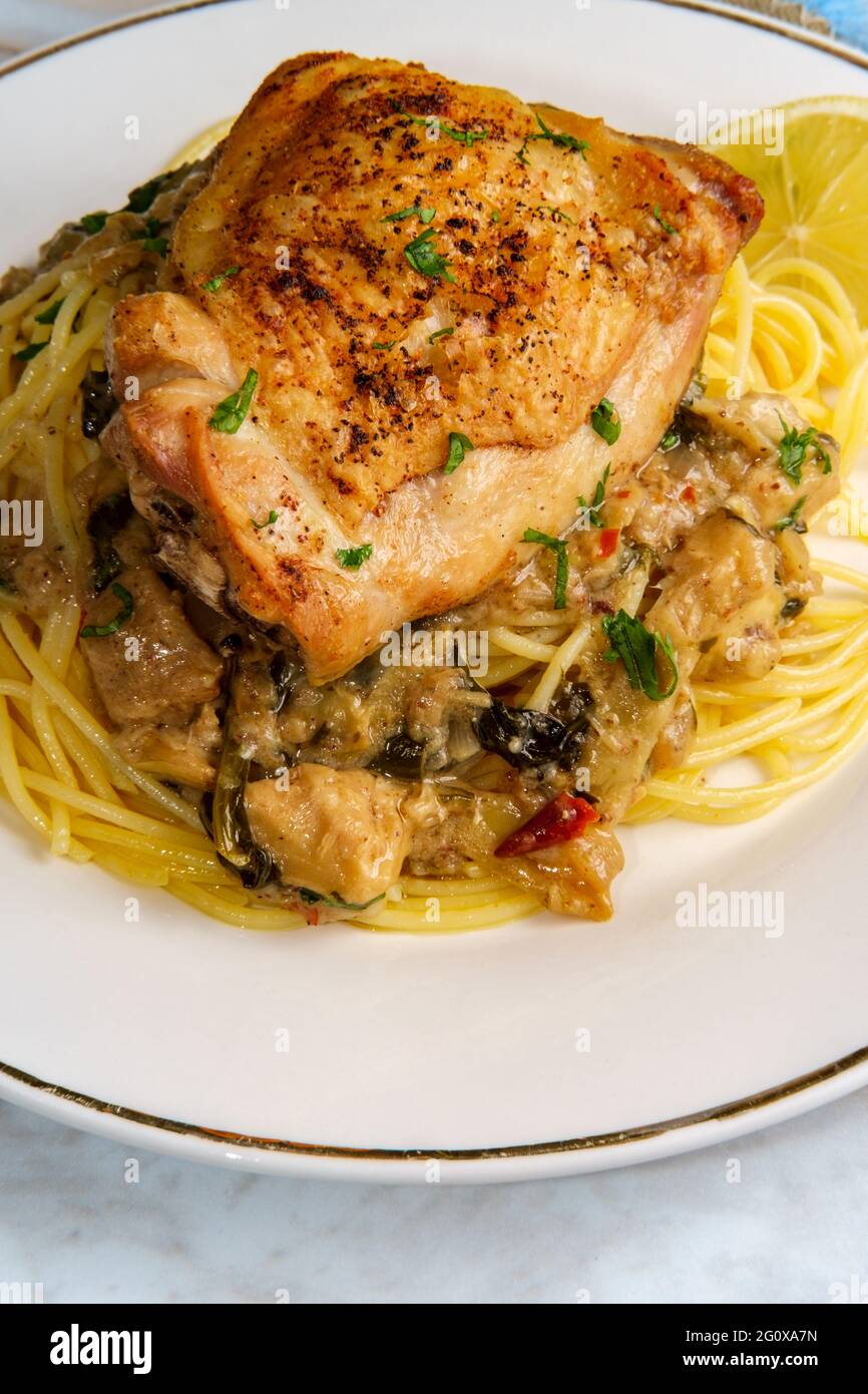 Cosce di pollo cotte croccanti in un cuore di carciofo di spinaci cremoso salsa Foto Stock