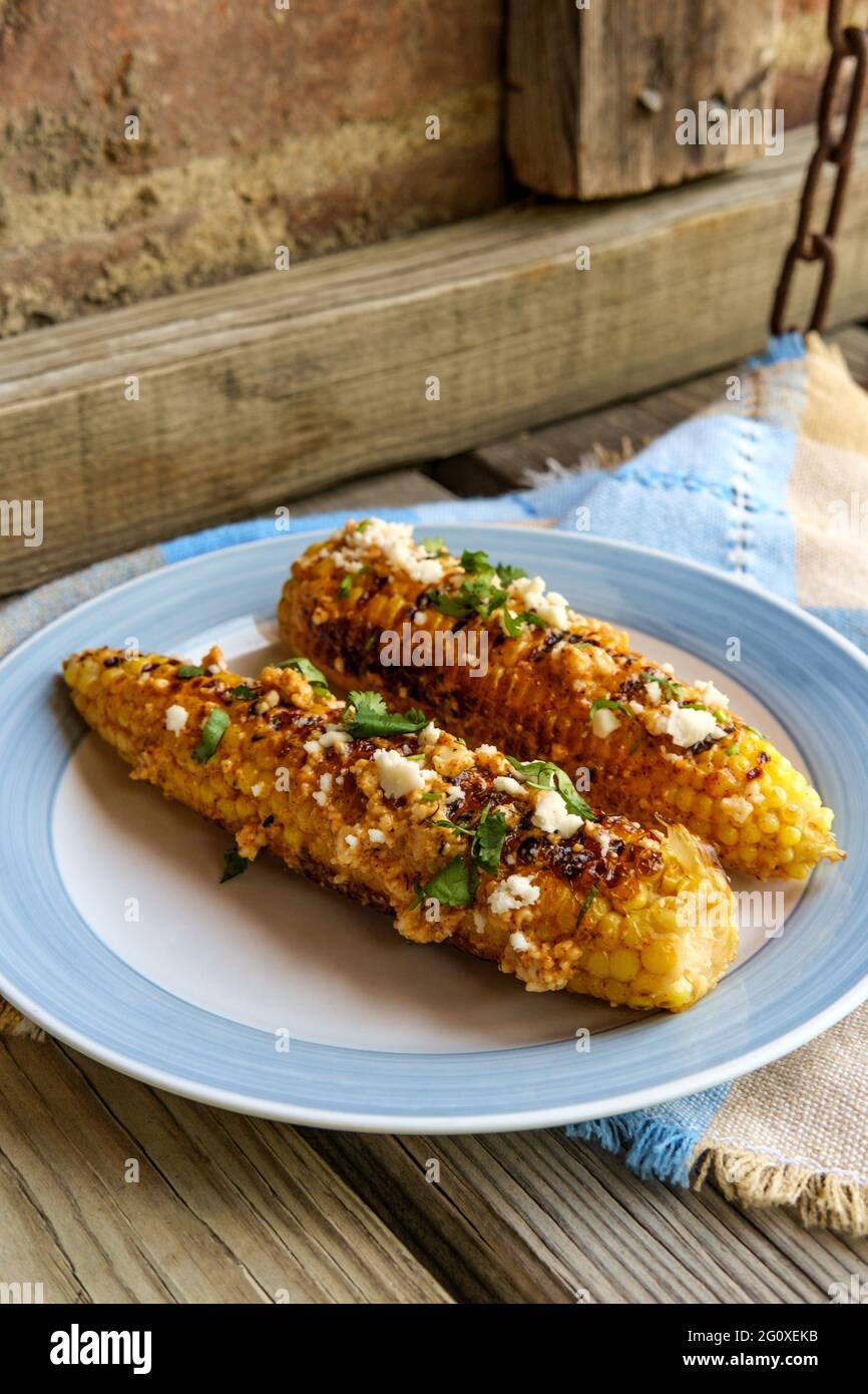 Mais messicano di strada conosciuto anche come elote servito con maionese di peperoncino e formaggio cotija Foto Stock