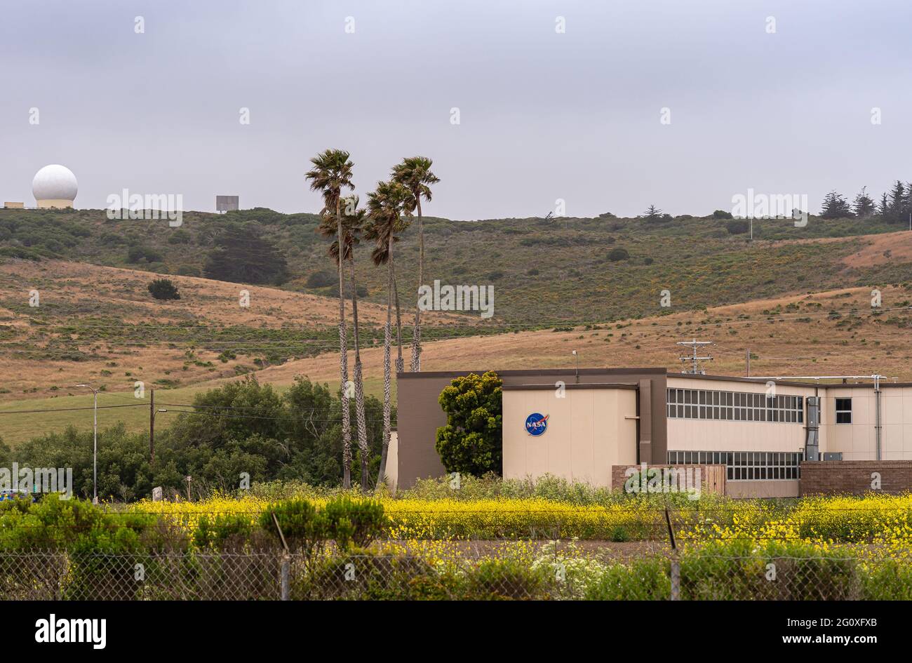 Lompoc, CA, USA - 26 maggio 2021: Base della forza spaziale Vandenberg. Closeup di NASA edificio e antenna set in paesaggio collinare verde sotto il cielo azzurro con Foto Stock