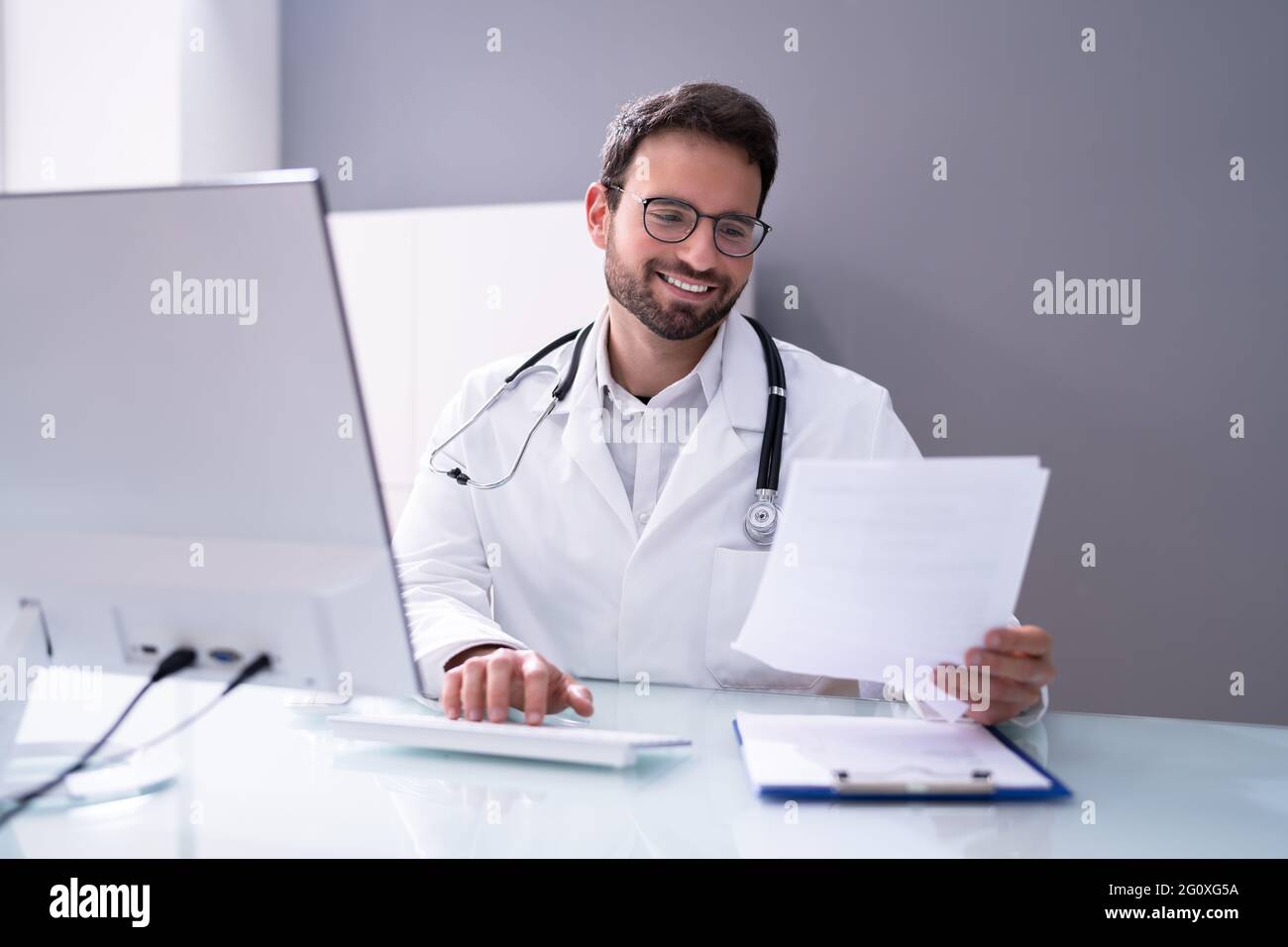 Happy Physician Doctor utilizzando il computer presso Office Desk Foto Stock