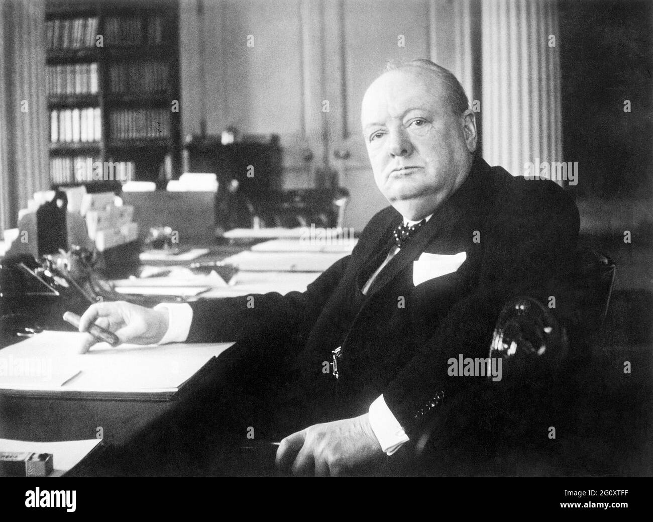 Un ritratto di Winston Churchill come primo ministro sedette alla sua scrivania nelle sale del Gabinetto al 10 Downing Street Foto Stock