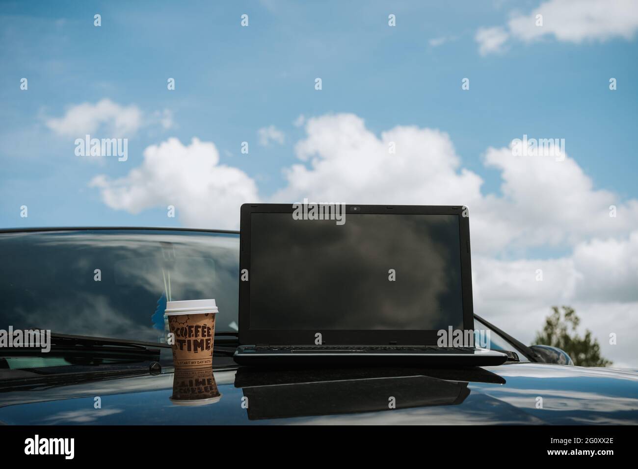 all'aperto lavorare su un computer portatile, con una tazza da caffè, posizione remota in natura con cielo e nuvole, connessione internet, libertà di freelance Foto Stock