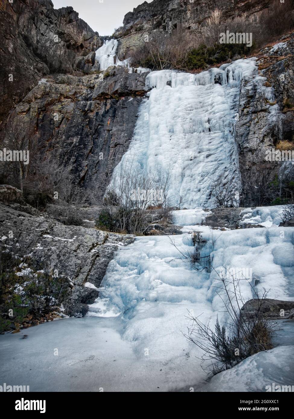 Cascata di ghiaccio tra pareti rocciose, nelle colline settentrionali di Guadalajara, cascata di despeñalagua, Valverde de los Arroyos, Spagna, verticale Foto Stock