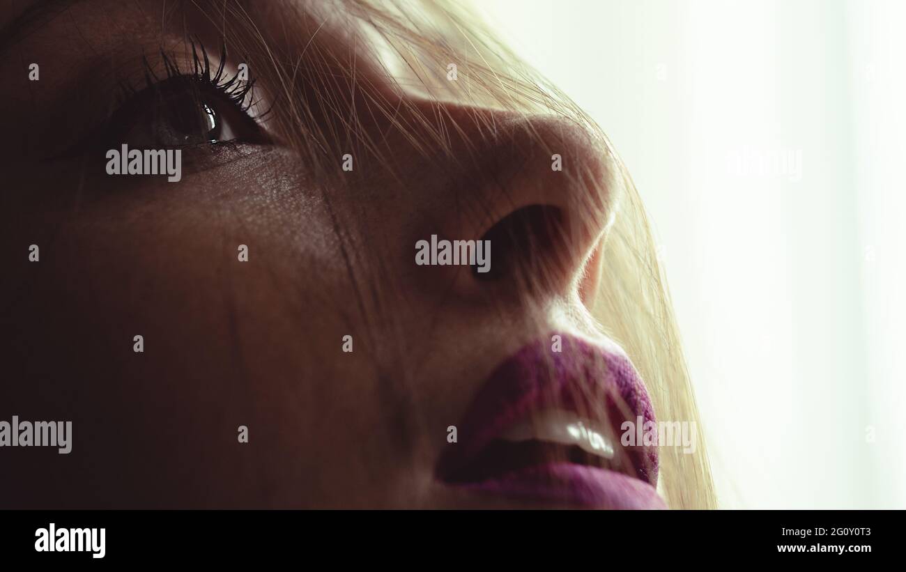 capelli disordinati nel viso di una donna con luce posteriore e occhi luminosi e rossetto viola Foto Stock