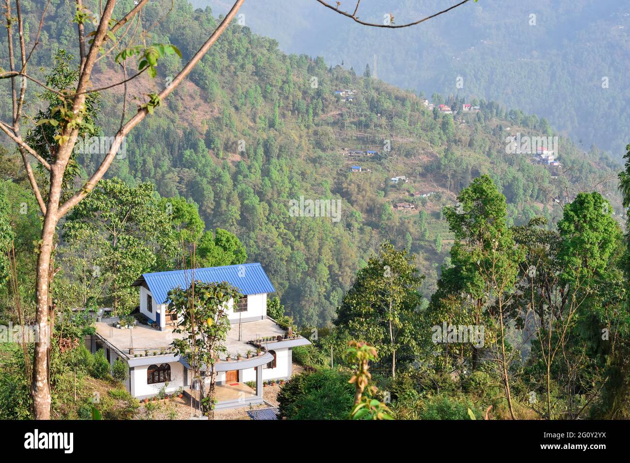 Himalyan villaggio paesaggio, un cottage soleggiato con tetto blu, pineta foresta. Foto Stock