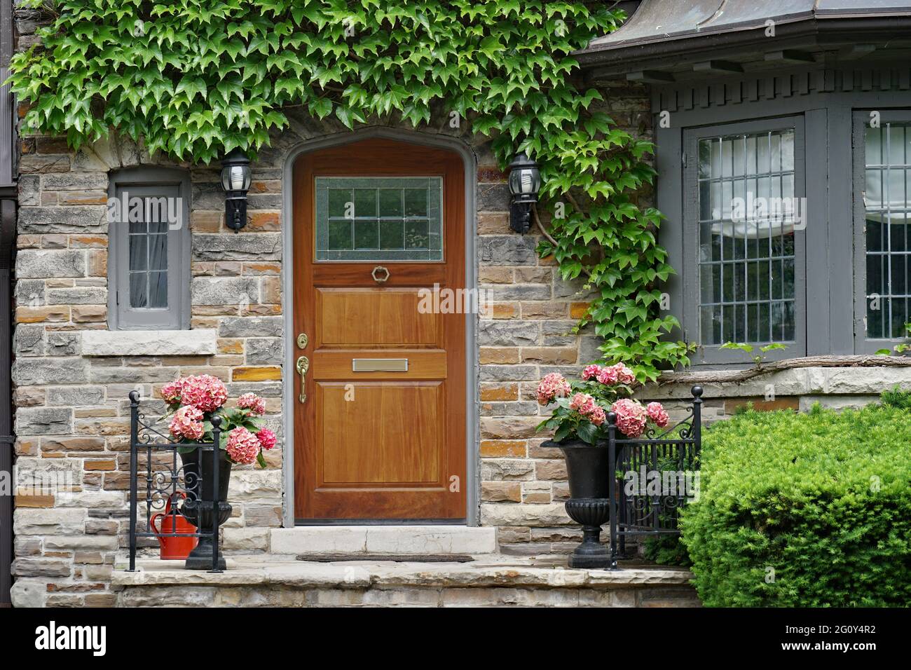 Casa con elegante porta anteriore in legno circondato da edera Foto Stock