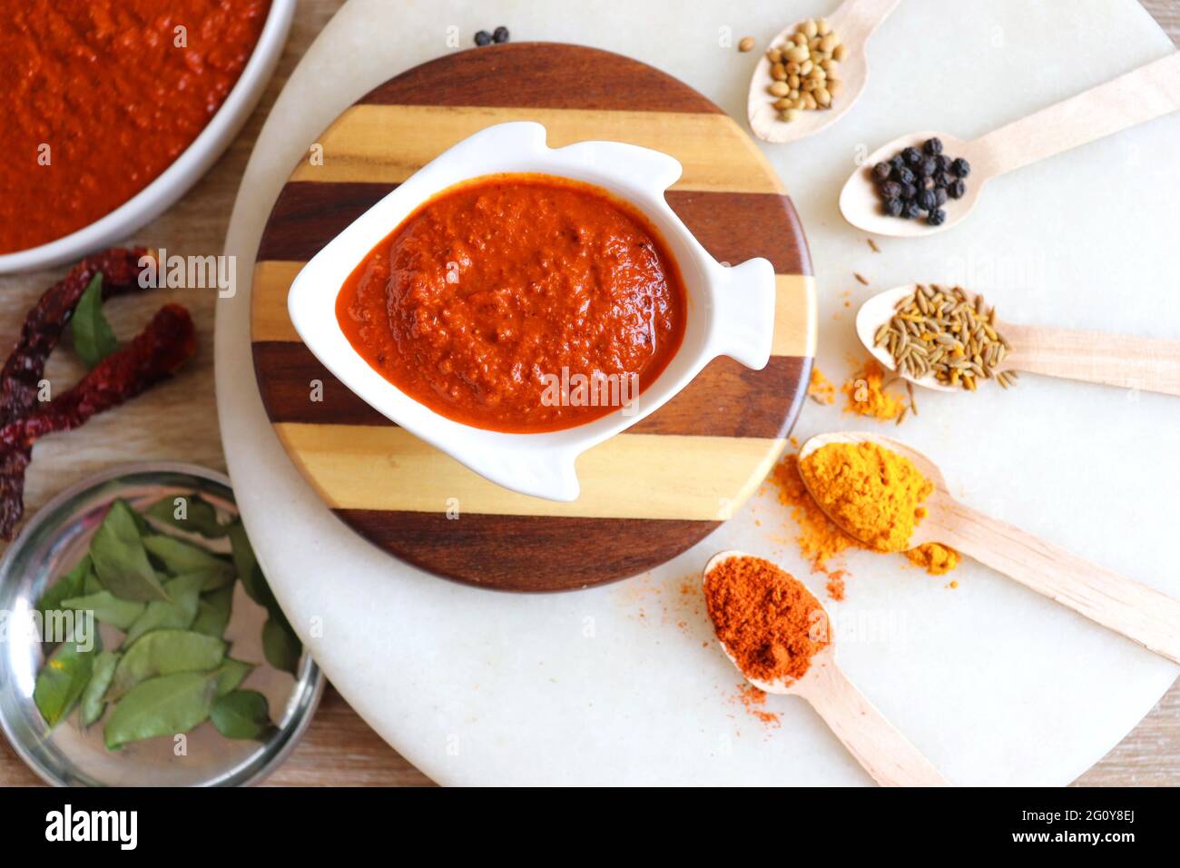 Cibo indiano - pasta di curry di pesce di Goan o masala di base di frutti di cocco rossi. Servito nella ciotola a forma di pesce. Ingredienti sullo sfondo con spazio per la copia. Foto Stock