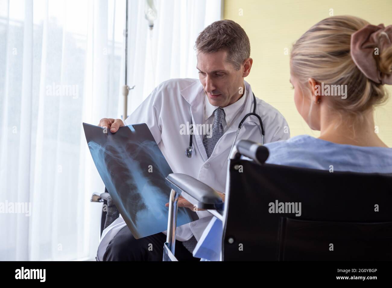 Medico che esamina la pellicola radiografica del torace della paziente in ospedale. Sindrome respiratoria o concetto di sintomo di polmonite virale Foto Stock