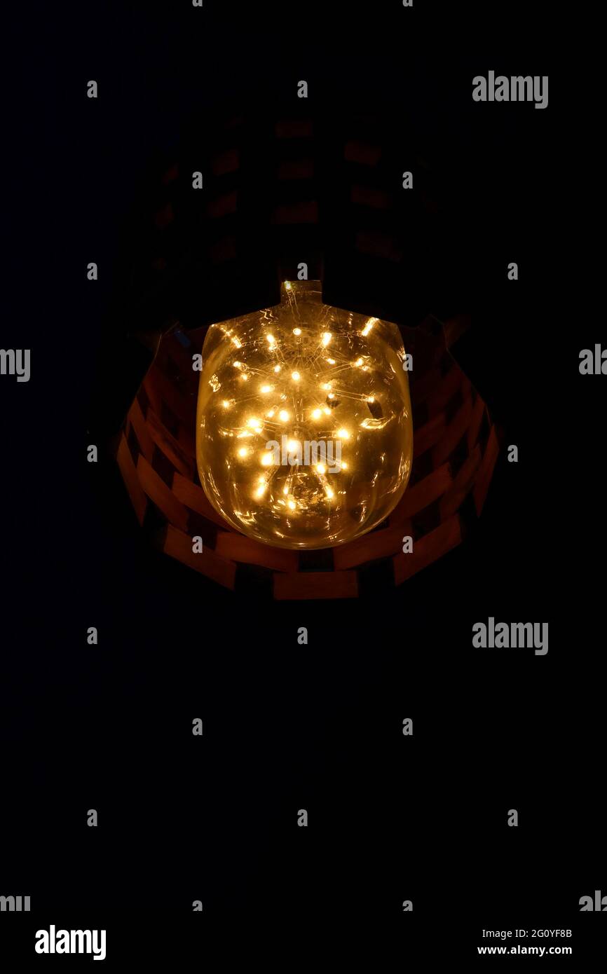 Lampada LED vintage, luminosa ed estetica, con gruppo LED arancione-giallo interconnesso isolato su sfondo scuro in condizioni di scarsa illuminazione Foto Stock