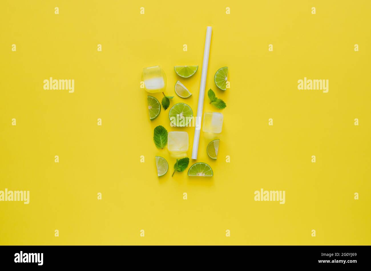 Cocktail Mojito con lime, foglie di menta, cubetti di ghiaccio e paglia di carta su sfondo giallo. Concetto minimo di bevanda estiva. Foto Stock