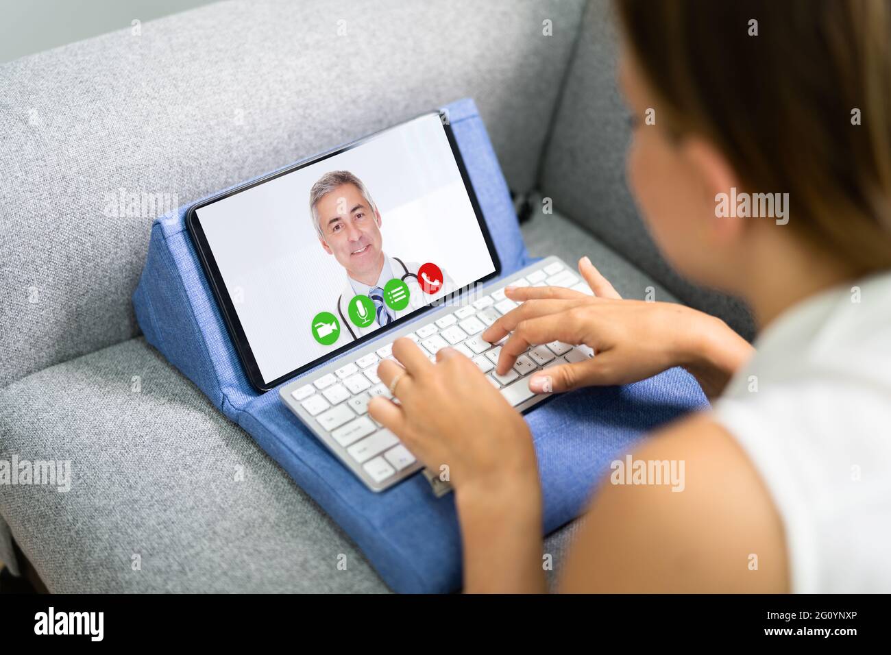 Donna che ha una chat video con Dottore Femminile su un tablet digitale a casa Foto Stock