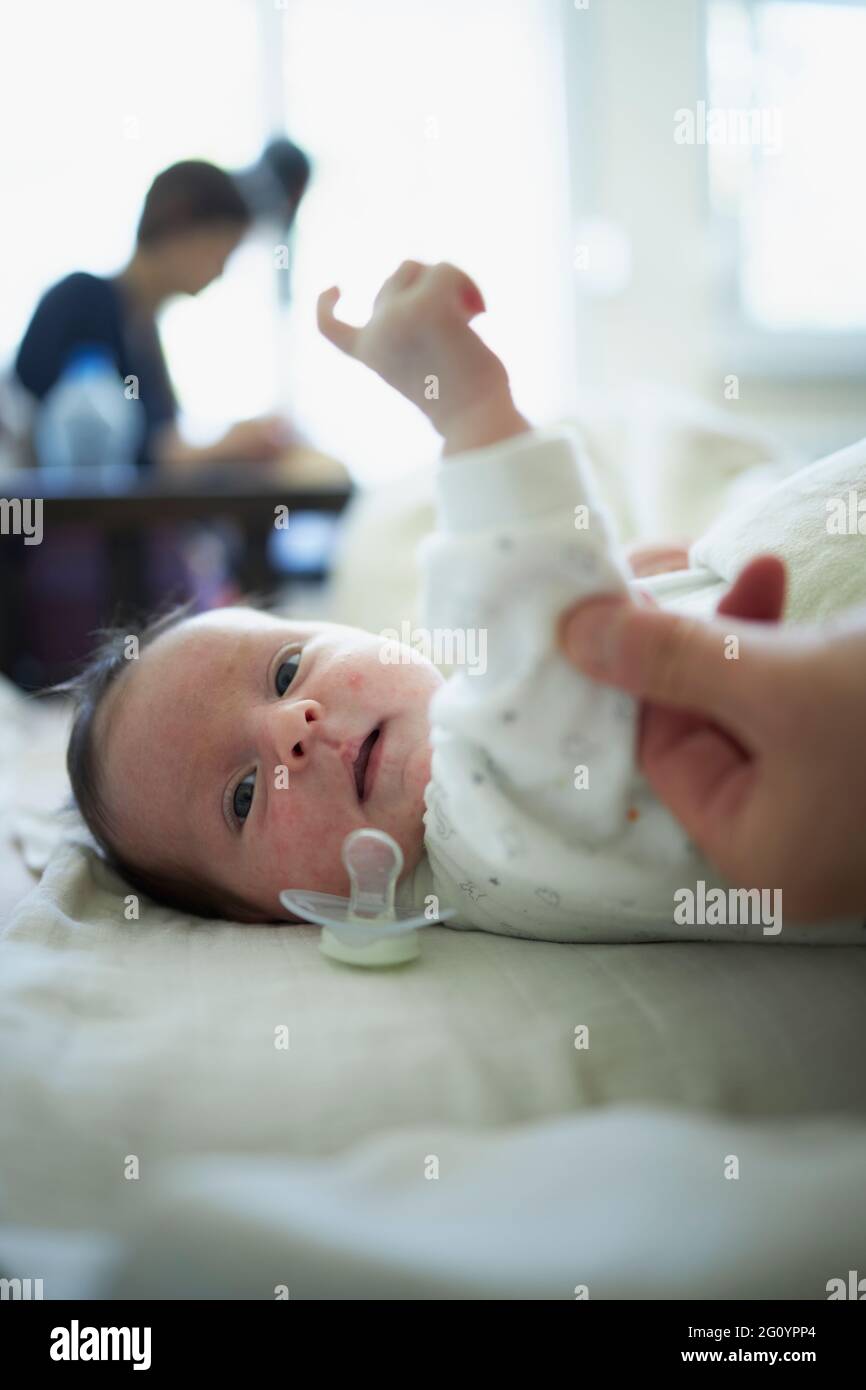 Neonato sdraiato a letto con un succhietto caduto fuori Foto Stock