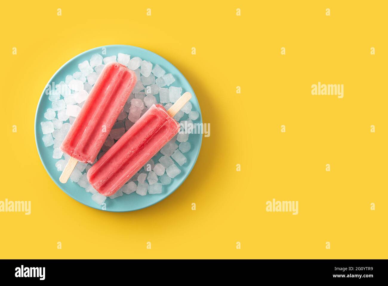 Popsicle di fragole con ghiaccio su sfondo giallo Foto Stock