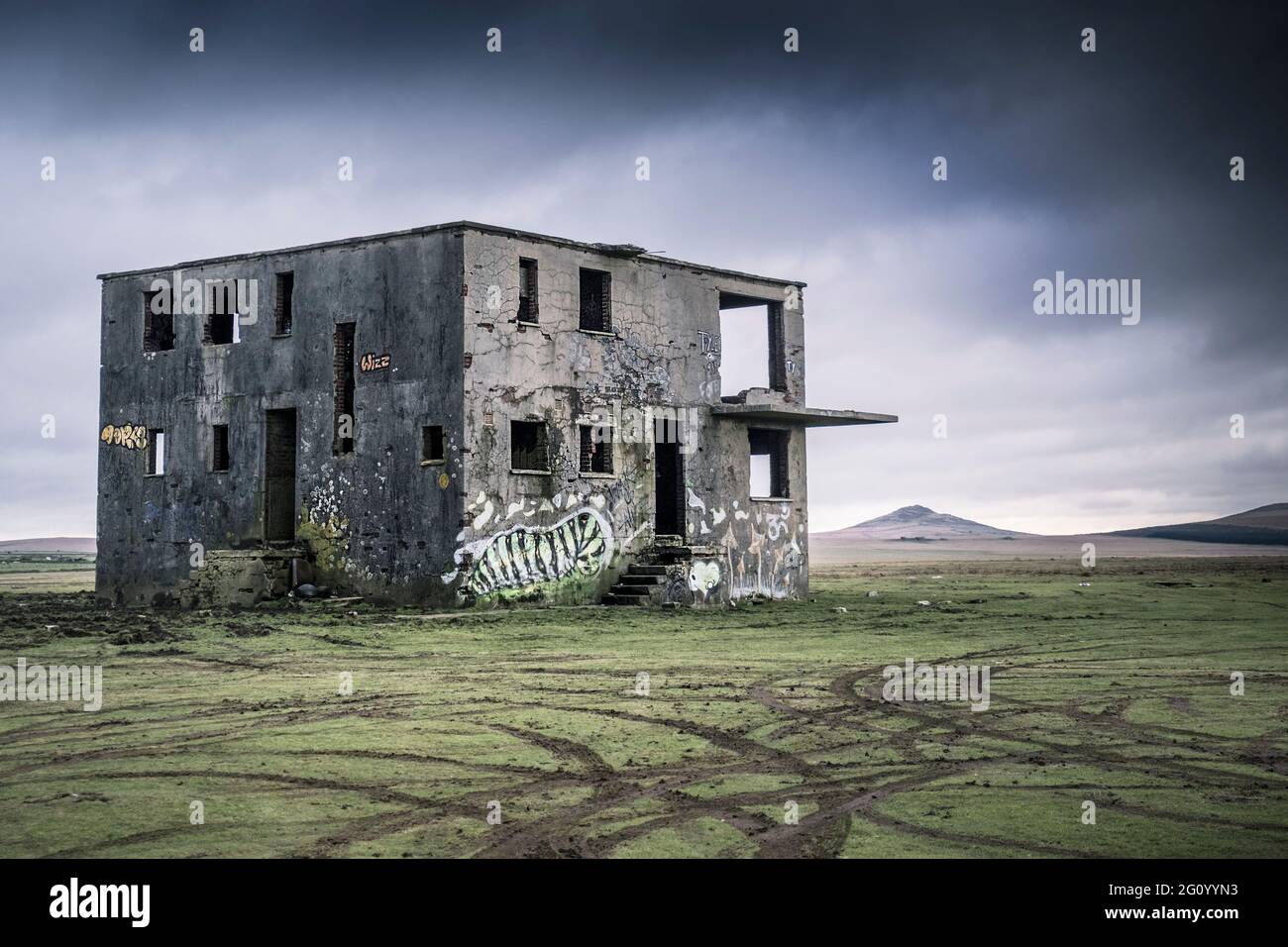 I segni degli pneumatici del veicolo nell'erba lasciata dai gioie di fronte alla torre di controllo derelict sul disutilizzato WW2 RAF Davidstow Airfield su Bodmin Moor in Foto Stock