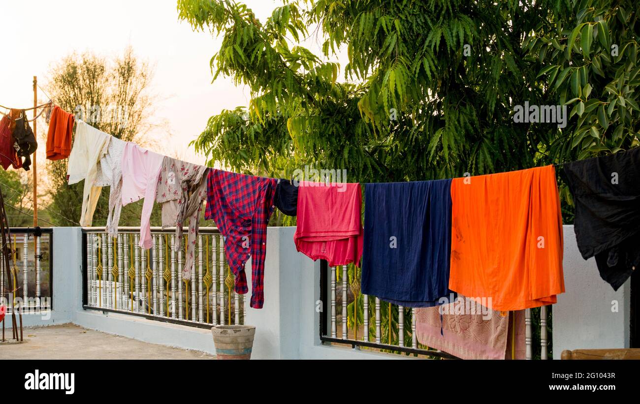 Sul tetto, corda con vestiti puliti all'aperto il giorno di lavanderia. Abiti colorati appesi in abiti. Foto Stock
