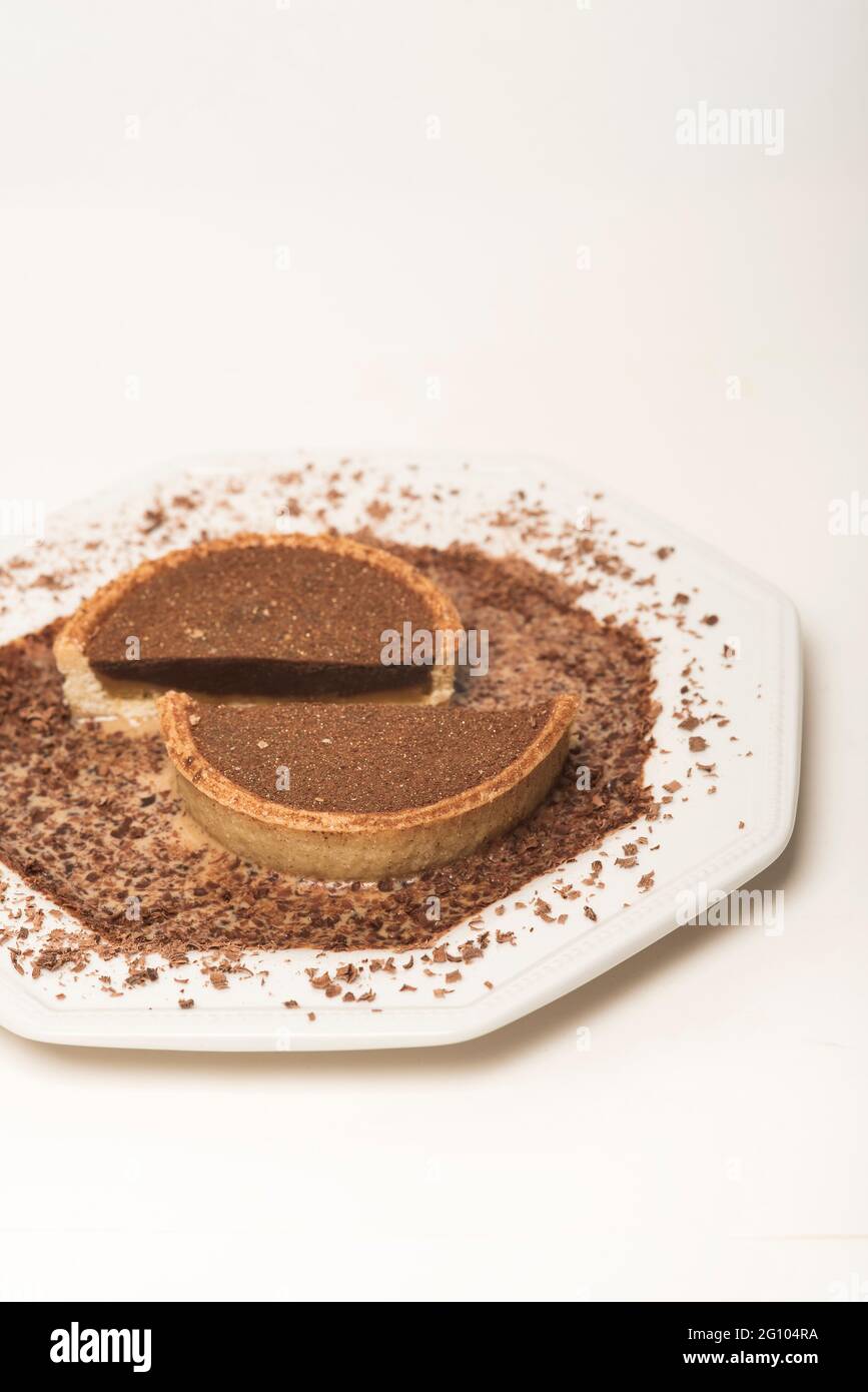 Strati di cioccolato e caramello che riempiono una torta di pasta frolla circondata da una leggera salsa di crema al caramello spolverata con cioccolato grattugiato. CopySpace. Foto Stock
