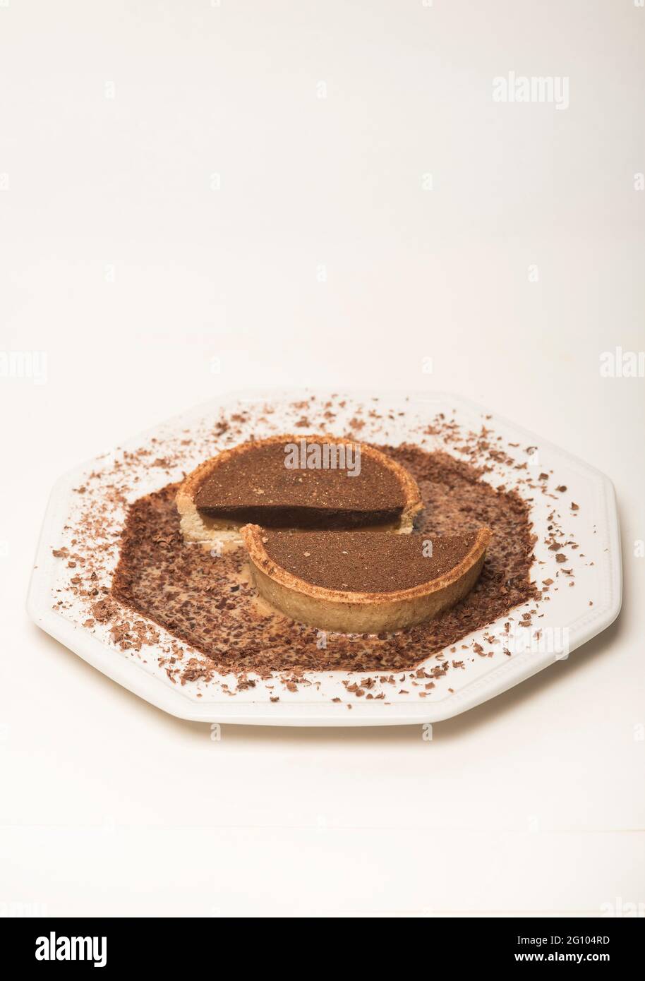 Strati di cioccolato e caramello che riempiono una torta di pasta frolla circondata da una leggera salsa di crema al caramello spolverata con cioccolato grattugiato. CopySpace. Foto Stock