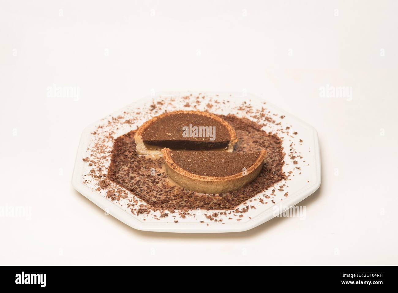 Strati di cioccolato e caramello che riempiono una torta di pasta frolla circondata da una leggera salsa di crema al caramello spolverata con cioccolato grattugiato. CopySpace. Foto Stock