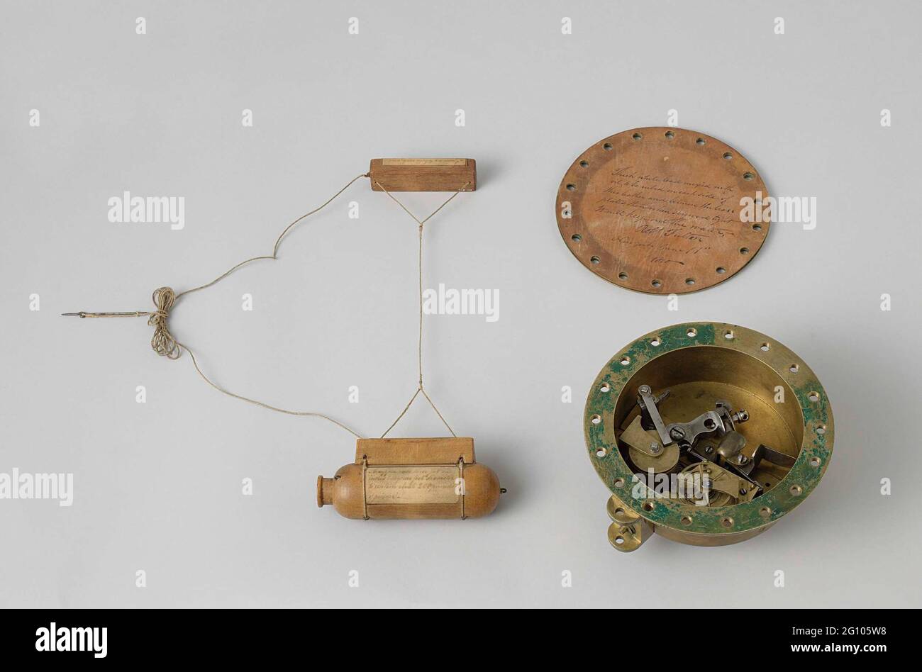 Time Fuse in una scatola e un modello di un Torpedo. Tempo meccanismo infiammatorio in una casa rotonda in ottone, terminato su un lato con una flangia cieca con guarnizione in pelle su cui una iscrizione. Il meccanismo infiammatorio del tempo è costituito da un blocco di selce con orologio. Il gallo, che è costantemente mantenuto sotto tensione dalla molla di battaglia sul tumbler, è trattenuto da una leva (l'asta) che è stata forgiata in un gancio alla testa del gallo; il tumbler e l'asta sono separati. L'asta è tenuta in posizione con una prolunga che poggia su un disco con una tacca. Questo disco è montato su un fourteon e funziona sotto t Foto Stock