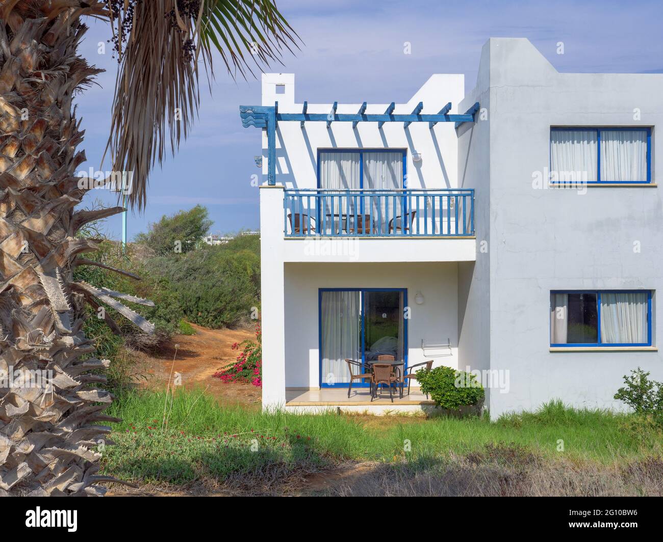 Villa in colori bianco e blu con terrazza aperta in tradizionale stile greco ad Ayia Napa, Cipro. Albero di palma che cresce nella parte anteriore. Foto Stock