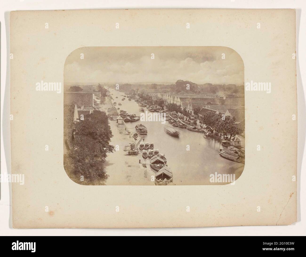 Willemskade e Kampong Baroe lungo il Kali Mas a Surabaya. Willemskade e Kampong Baroe lungo il Kali Mas a Surabaya, vista al mare. Lasciato in primo piano una gru sulla banchina. Molte navi sono ormeggiate e un certo numero di barche verso il mare, che si può vedere in lontananza. Parte dell'album fotografico dei produttori di Surabayasche Vereeniging van Sugar offerto a Frederik Beyerinck, residente a Surabaya. Foto Stock