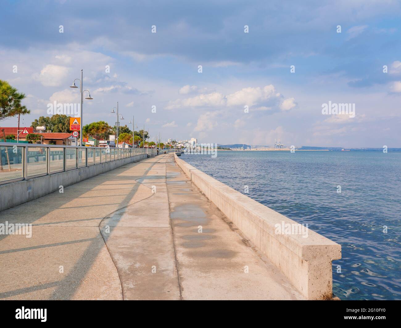 Lunga passeggiata vuota in cemento lungo il mare blu mediterraneo della città di Larnaca, Cipro. Tranquillo paesaggio marino con cielo nuvoloso sopra l'acqua Foto Stock