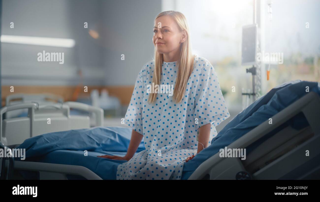 Modern Hospital Ward: Bella paziente caucasico femminile che riposa su un letto, completamente in recupero dopo un intervento chirurgico riuscito, malattia o Coronavirus lei Foto Stock