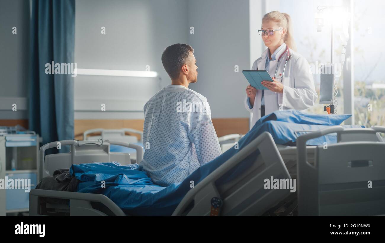Hospital Ward: Seduta sul letto paziente maschio caucasico ascolta il medico femminile esperto che spiega i risultati del test, dà consigli, prescrive la medicina Foto Stock