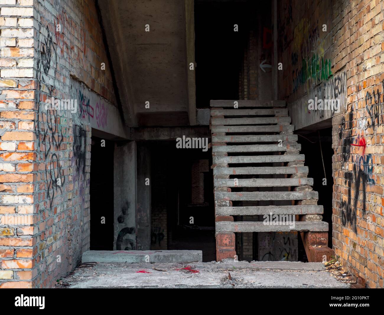 La scalinata all'interno di una costruzione sospesa incompiuta di un vecchio edificio in mattoni sporchi e logoro con graffiti sulle pareti nel centro di Kiev. Foto Stock