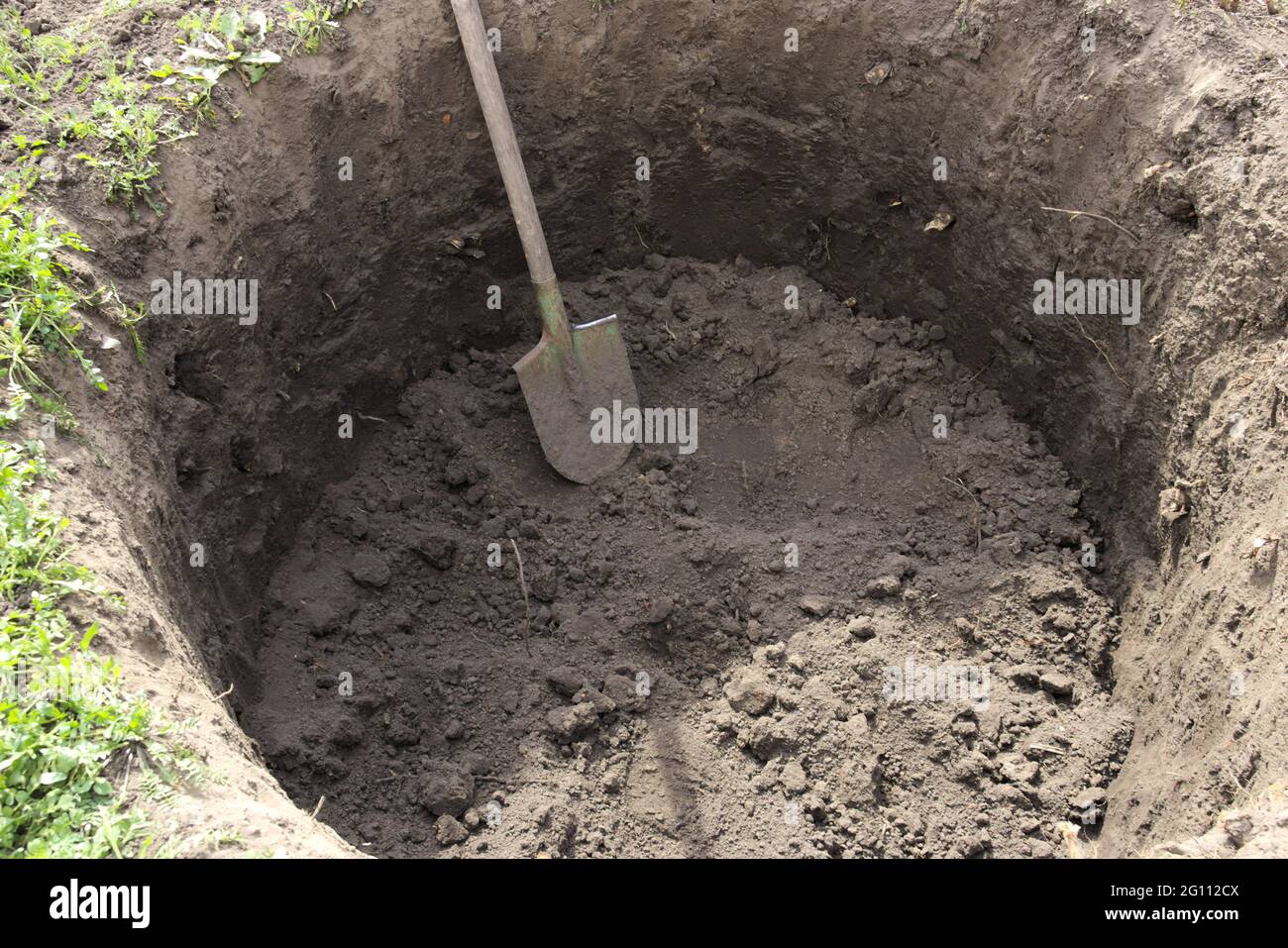 Fossa profonda nel terreno. Nella buca si trova una pala. Scavare un foro. Foto Stock