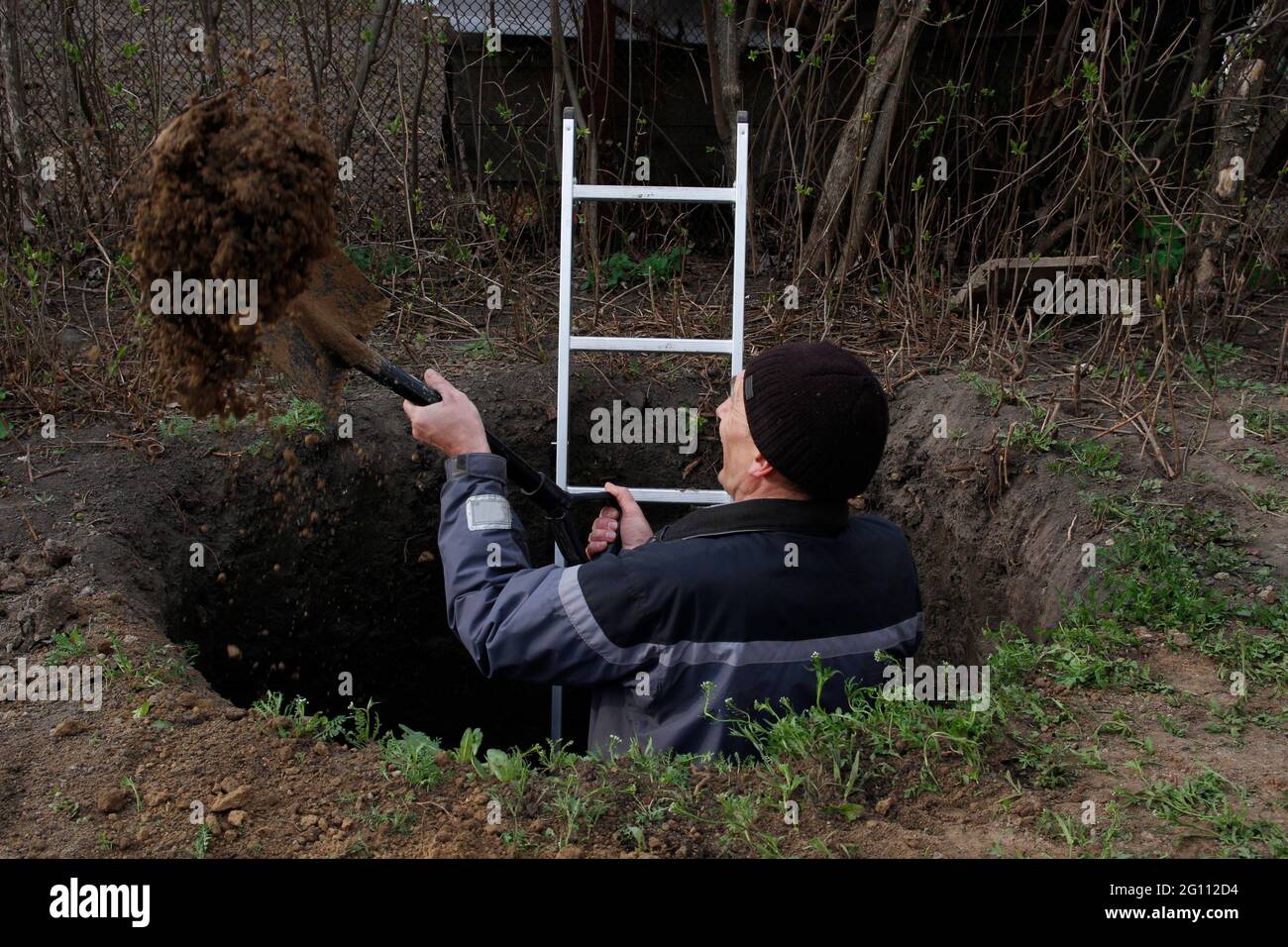 L'uomo scava una buca enorme. Nelle sue mani tiene una pala, accanto a un uomo è una scala. Foto Stock