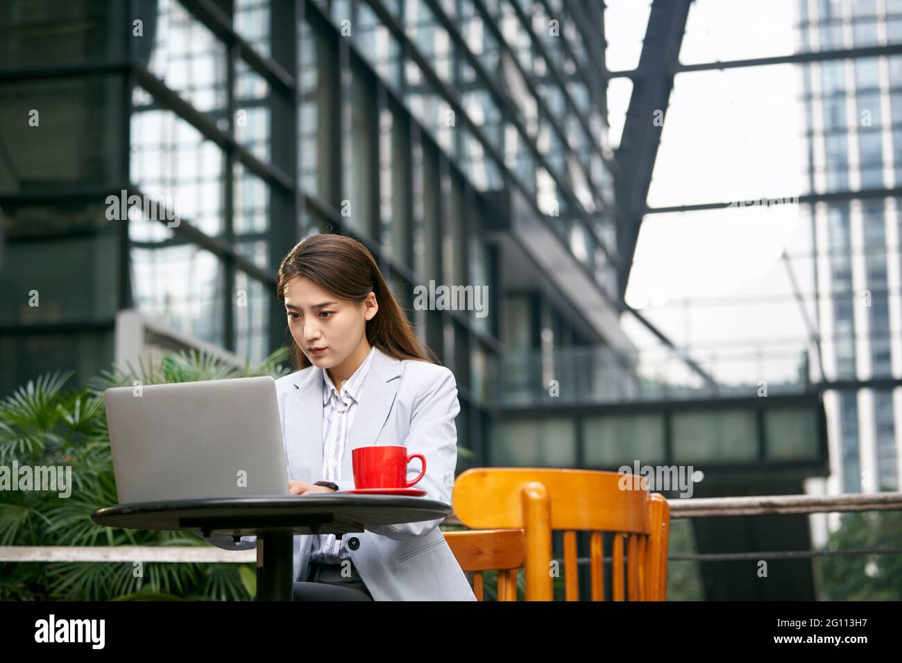 giovane donna d'affari asiatica che lavora all'aperto in una caffetteria utilizzando un computer portatile computer Foto Stock