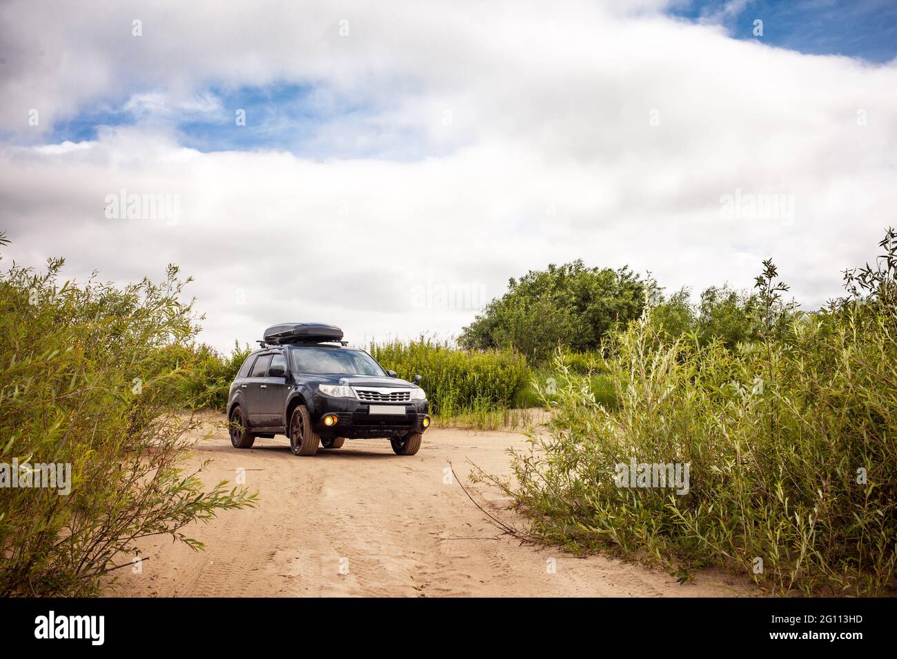 Black Subaru Forester sulla costa sabbiosa del fiume. Foto Stock
