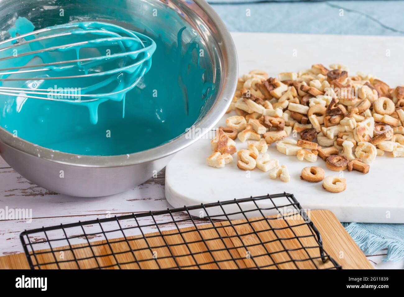 panna a ghiaccio blu montata in una ciotola di metallo su un tavolo con biscotti appena sfornati e cartone di metallo che asciuga Foto Stock