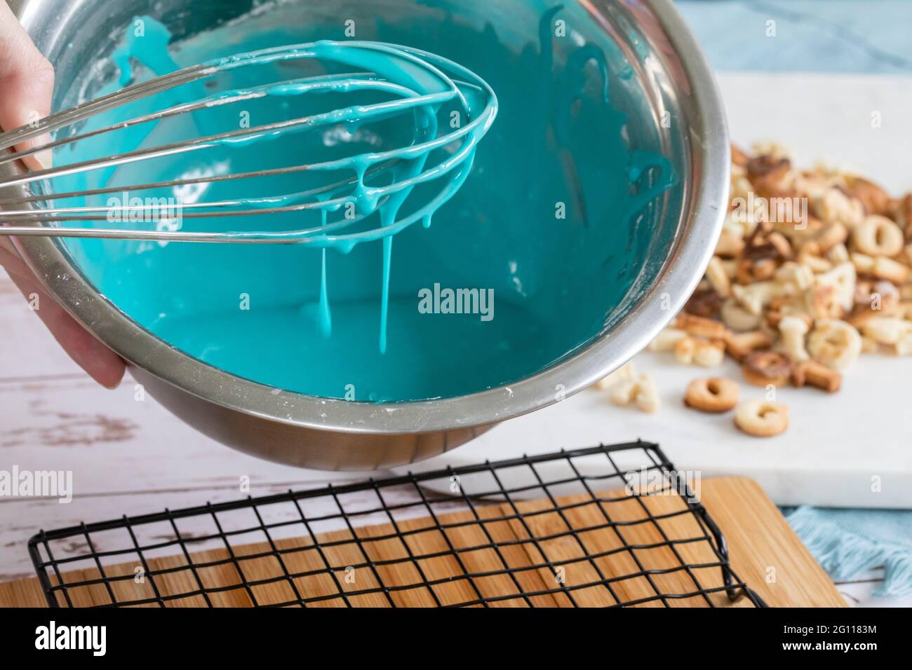 panna a ghiaccio blu montata in una ciotola di metallo su un tavolo con biscotti appena sfornati e tavola da essiccazione Foto Stock