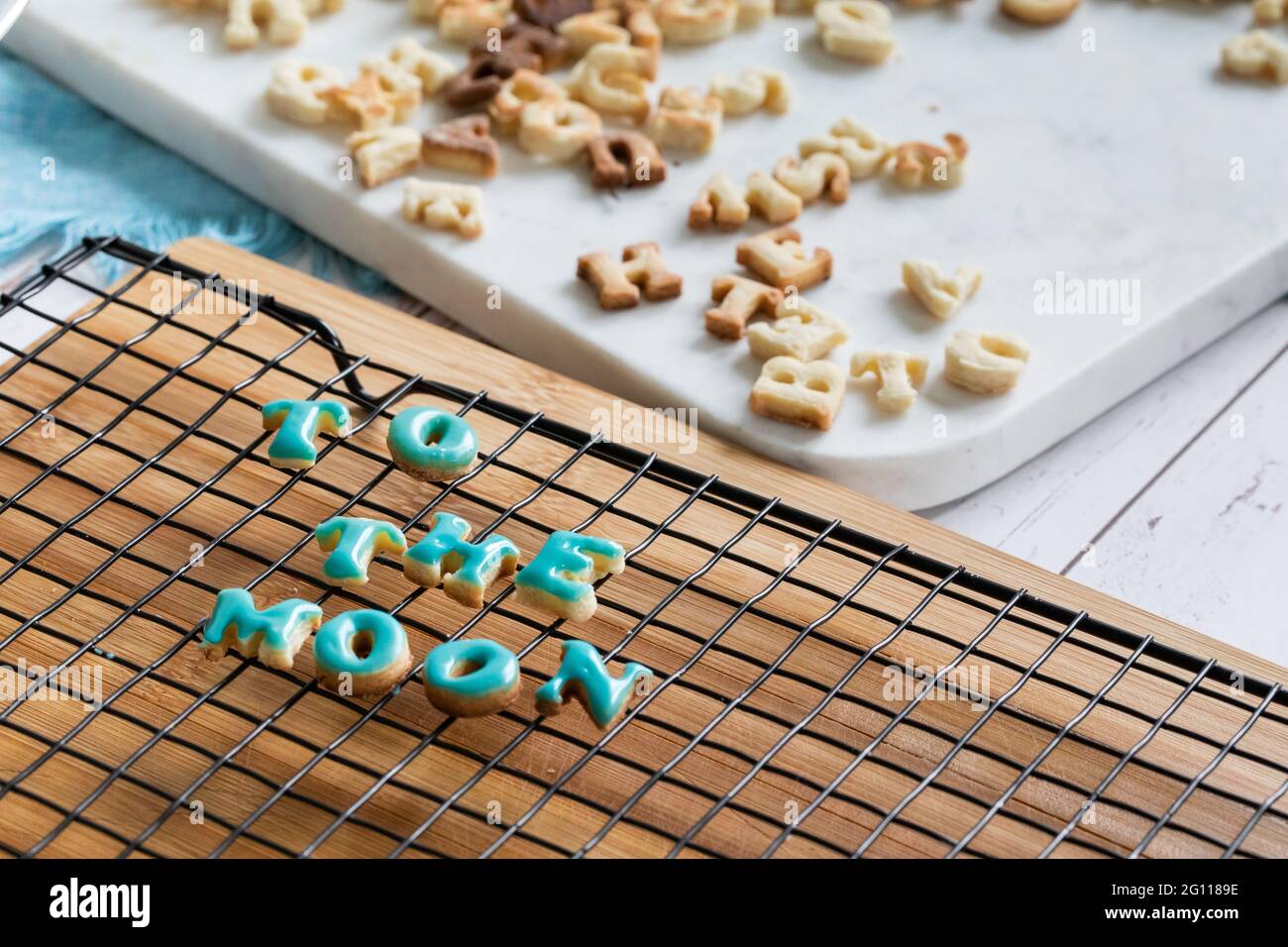 alla luna scritta in biscotti che asciugano su una griglia metallica su una tavola di legno con ghiaccio blu Foto Stock