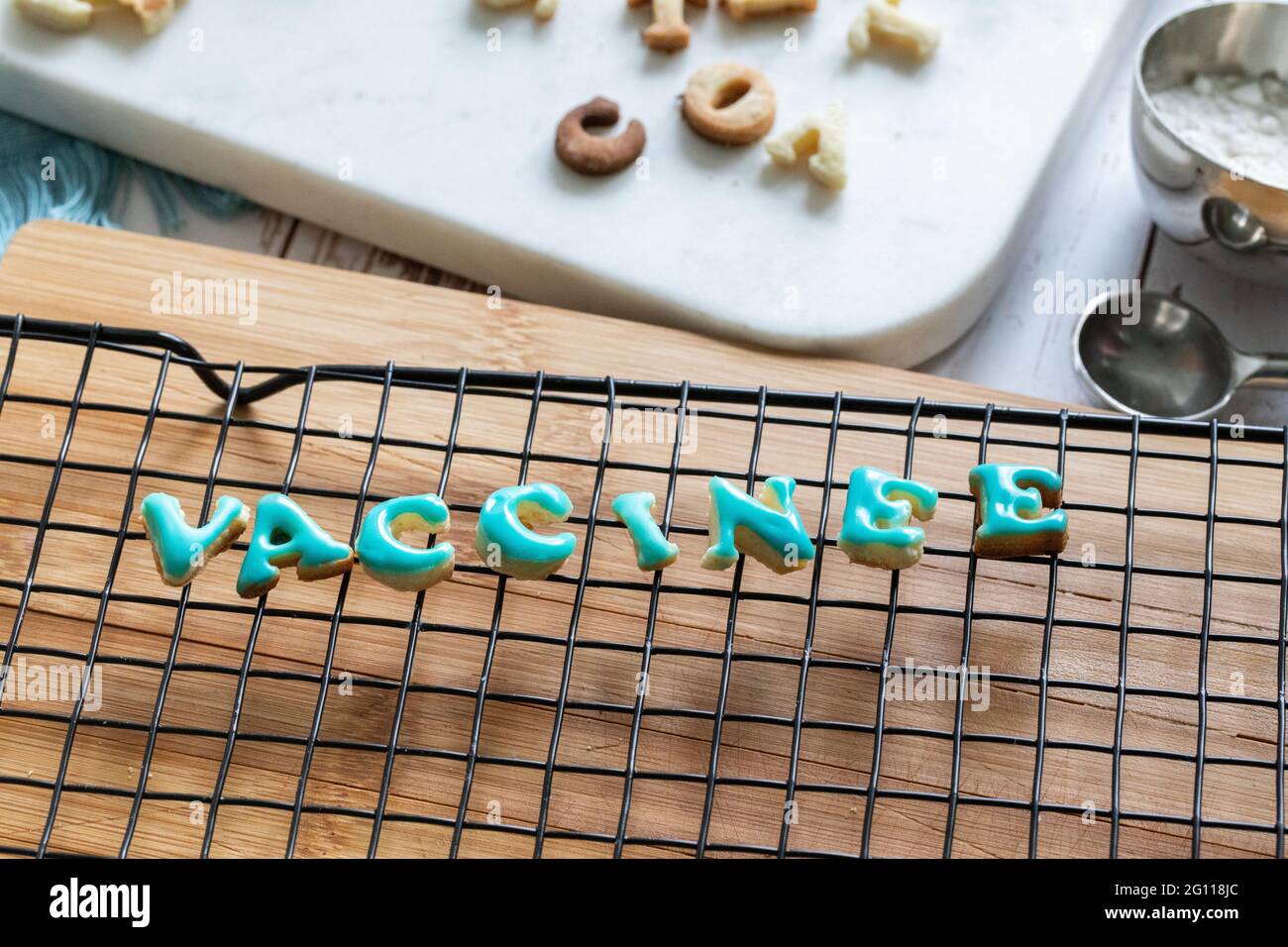 vaccinato in francese scritto in biscotti che asciugano su una griglia di metallo su una tavola di legno con ghiaccio blu Foto Stock