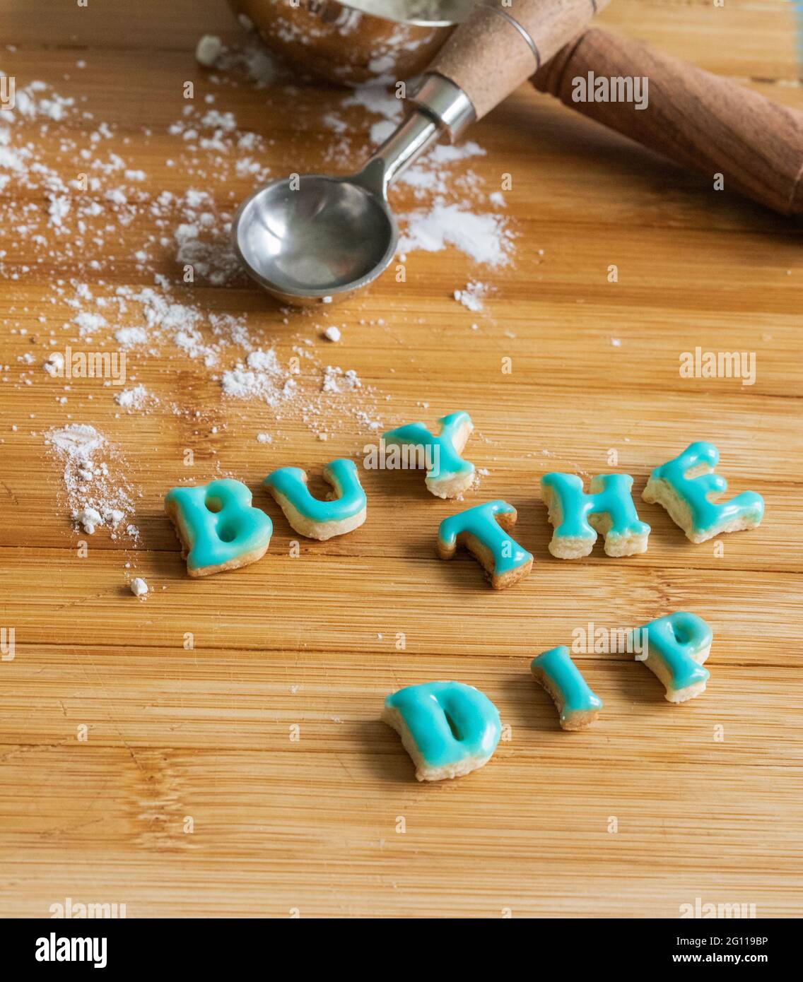 acquista il bagno scritto in biscotti con glassa blu su un tagliere di legno con misurino e farina Foto Stock