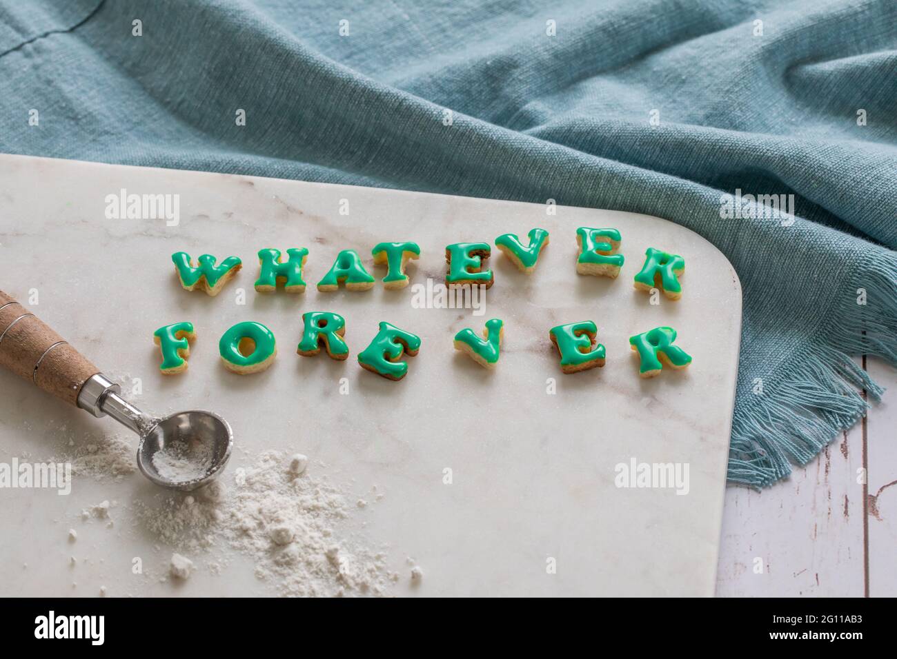 Qualsiasi cosa scritta per sempre in biscotti verdi su una tavola di marmo su un tavolo con un panno blu e misurino cucchiaio Foto Stock