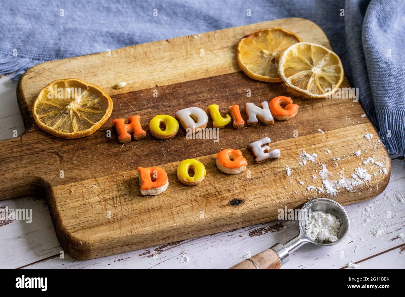 detto popolare nella comunità di valuta online frase fatta di giallo arancio e biscotti bianchi su un piatto di legno con un cucchiaio di misurazione e un Foto Stock