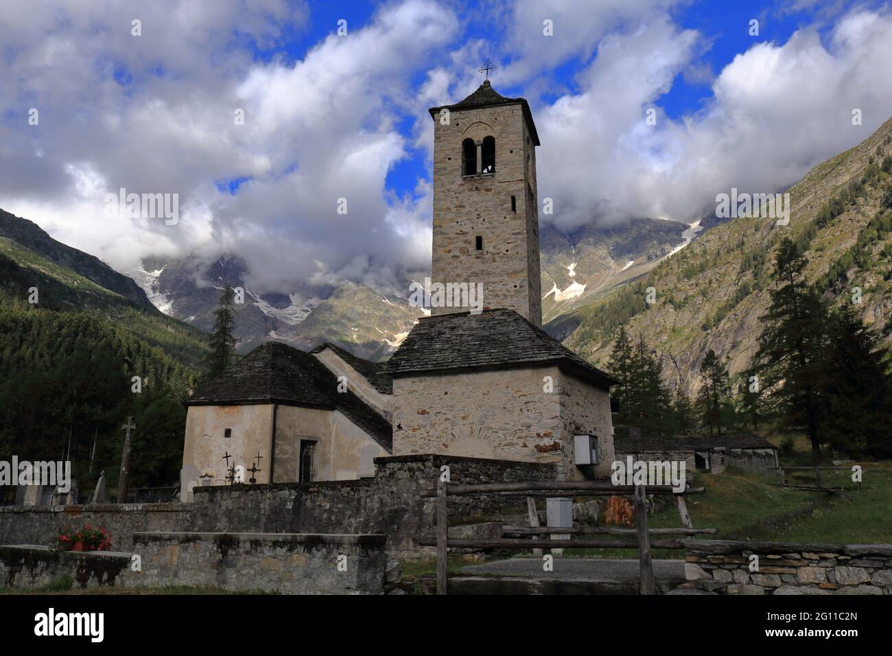 Vista della splendida Vecchia Chiesa di Macugnaga, con montagne e nuvole sullo sfondo. Molto bella. Foto Stock