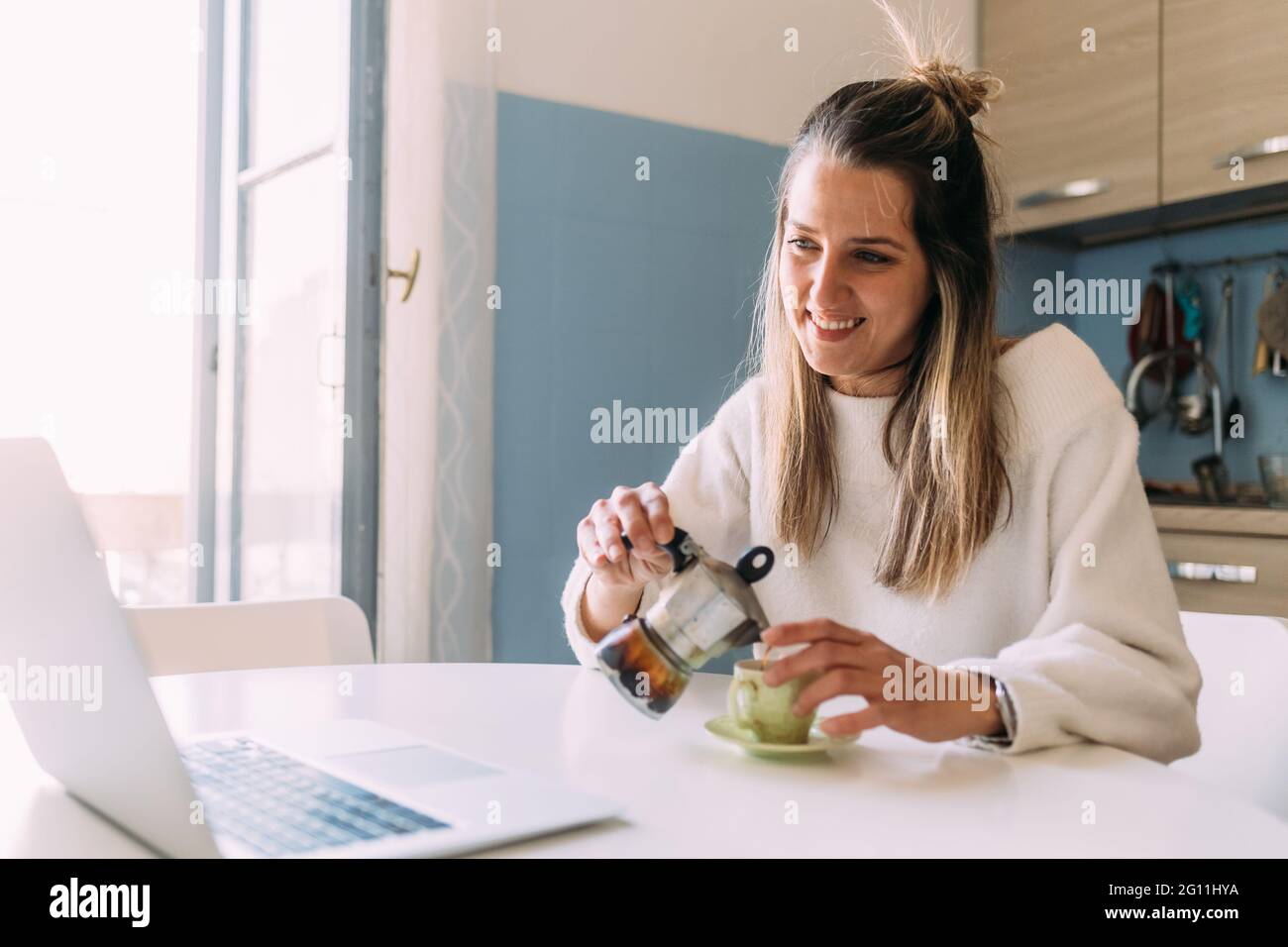 Italia, giovane donna che beve caffè e guarda il computer portatile Foto Stock