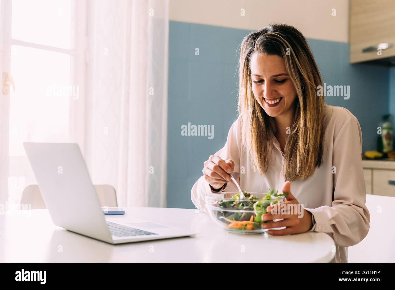 Italia, Donna mangiare insalata in cucina Foto Stock