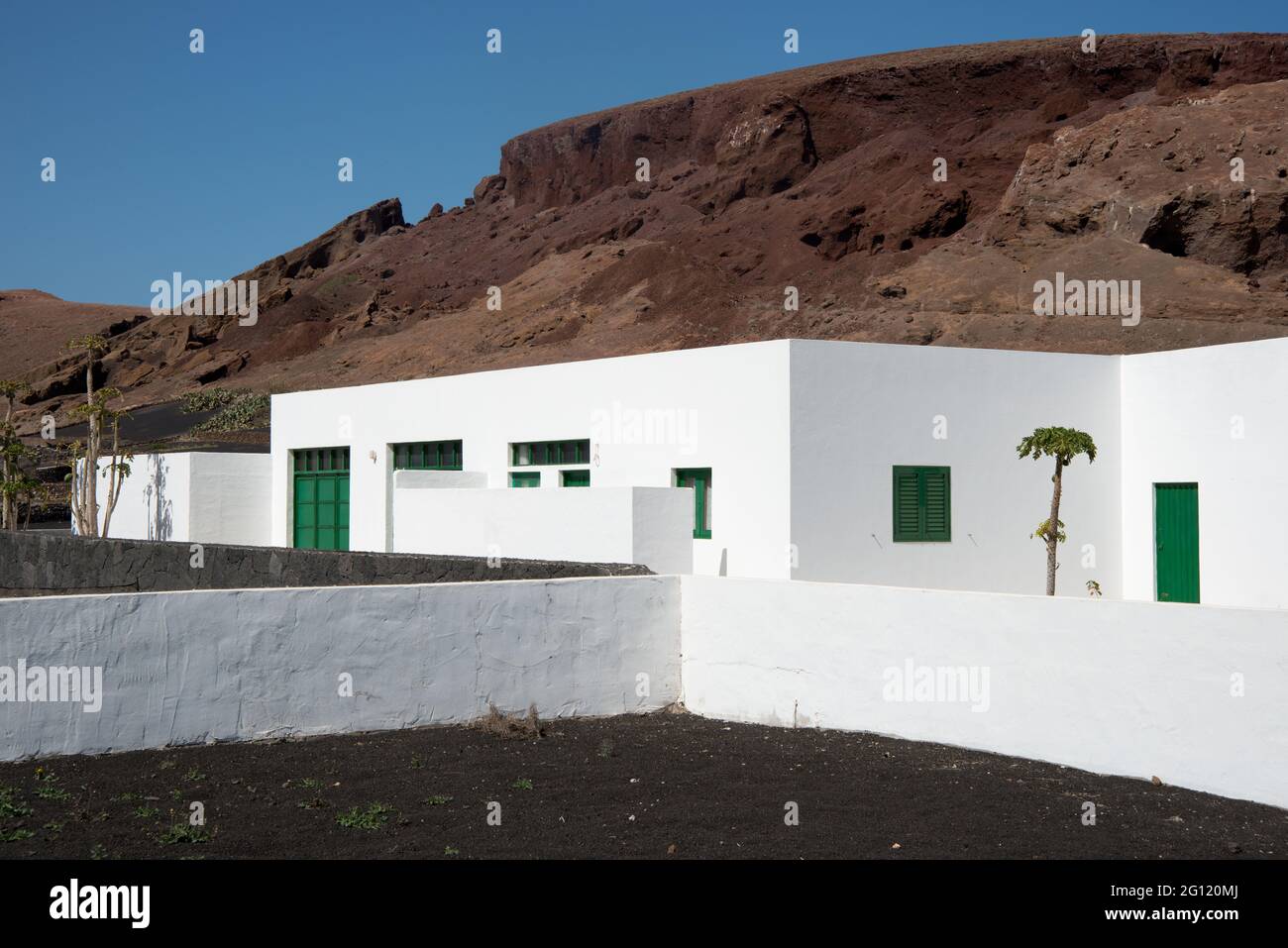 Tradizionale casa bianca a Lanzarote. Terra vulcanica, porta verde e finestre. Isole Canarie, Spagna, europee Foto Stock