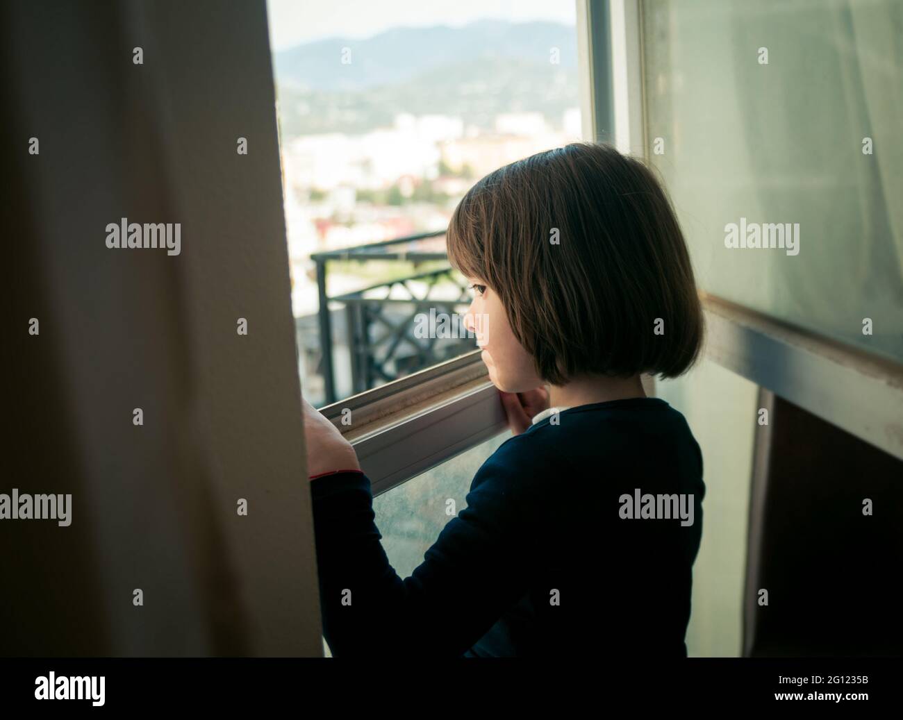 Bambina guardando fuori dalla finestra Foto Stock