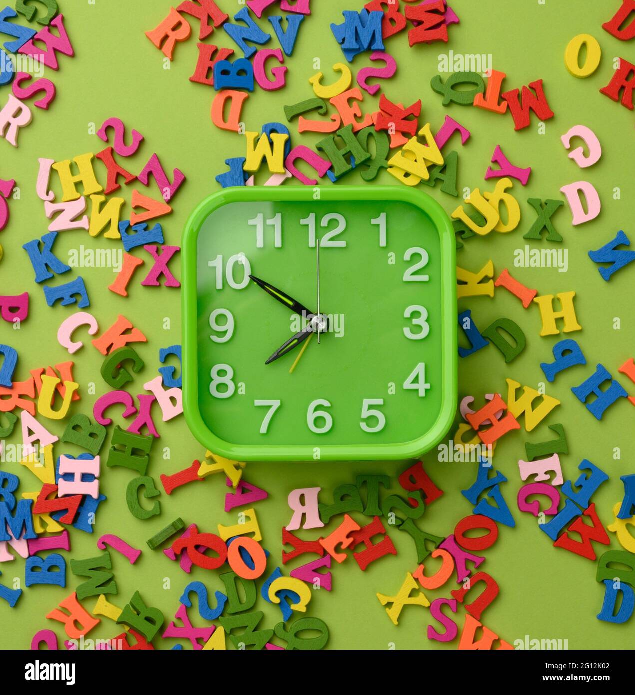 sveglia quadrata e lettere multicolore in legno dell'alfabeto inglese su  sfondo verde, vista dall'alto Foto stock - Alamy