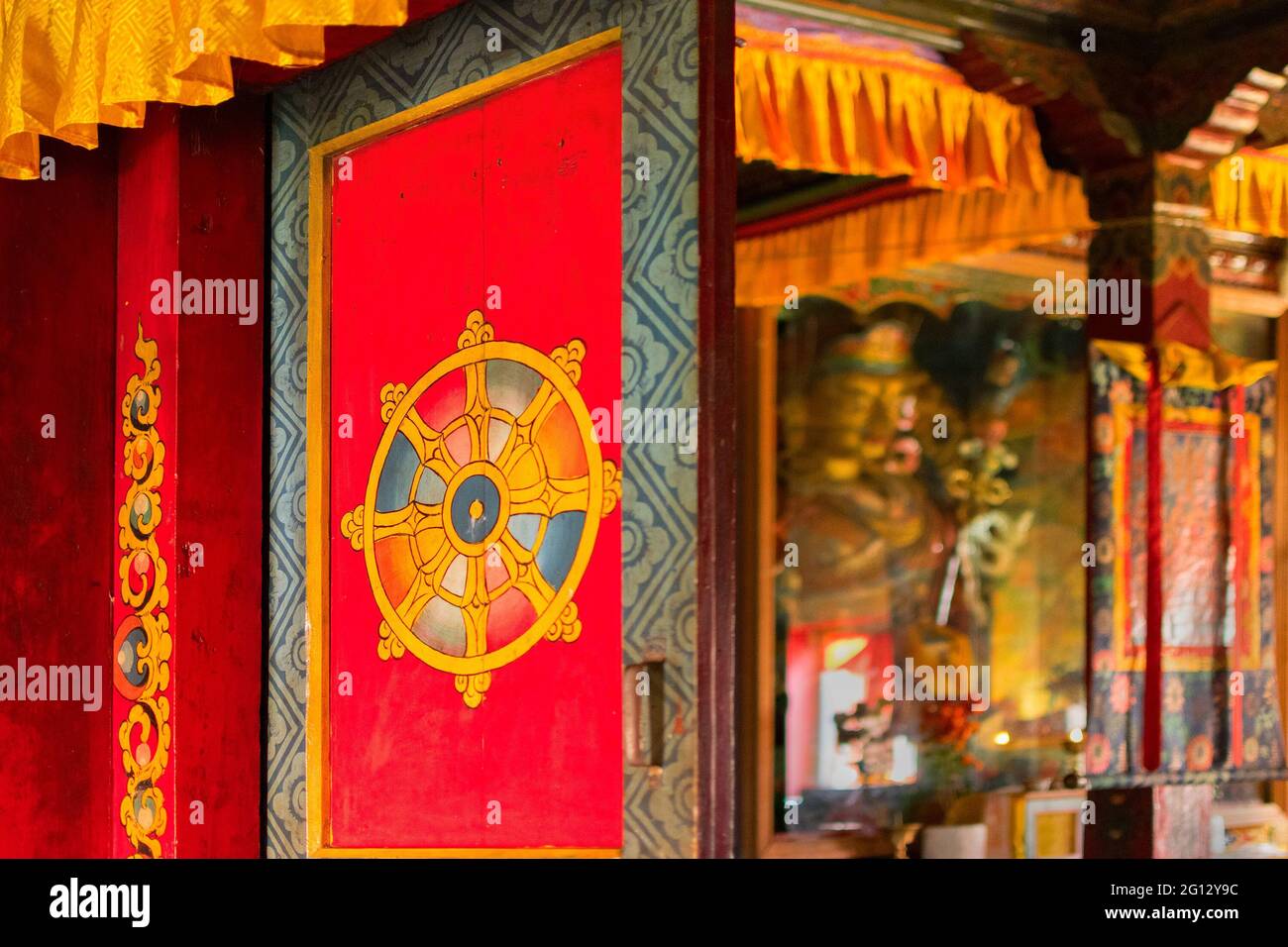 Porta di colore rosso di un monastero con simbolo artistico religioso buddista su di esso, Statua del Buddha di Goutama visto all'interno, Monastero di Sikkim - Sikkim, Indi Foto Stock