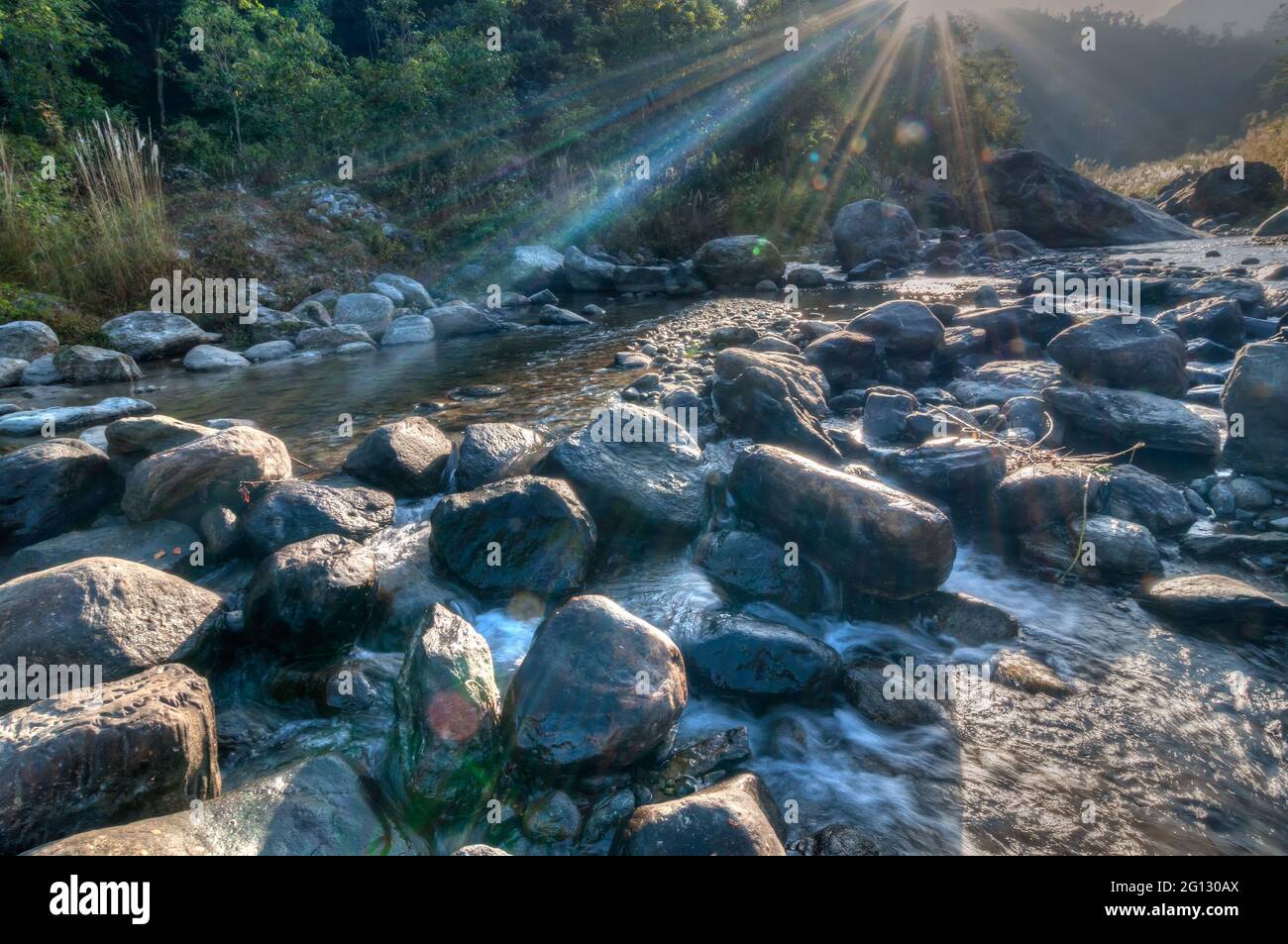 Fiume acqua che scorre attraverso le rocce all'alba, raggi di luce del sole sull'acqua, bel fiume Reshi, Sikkim, India - stock immagine dei fiumi in India Foto Stock