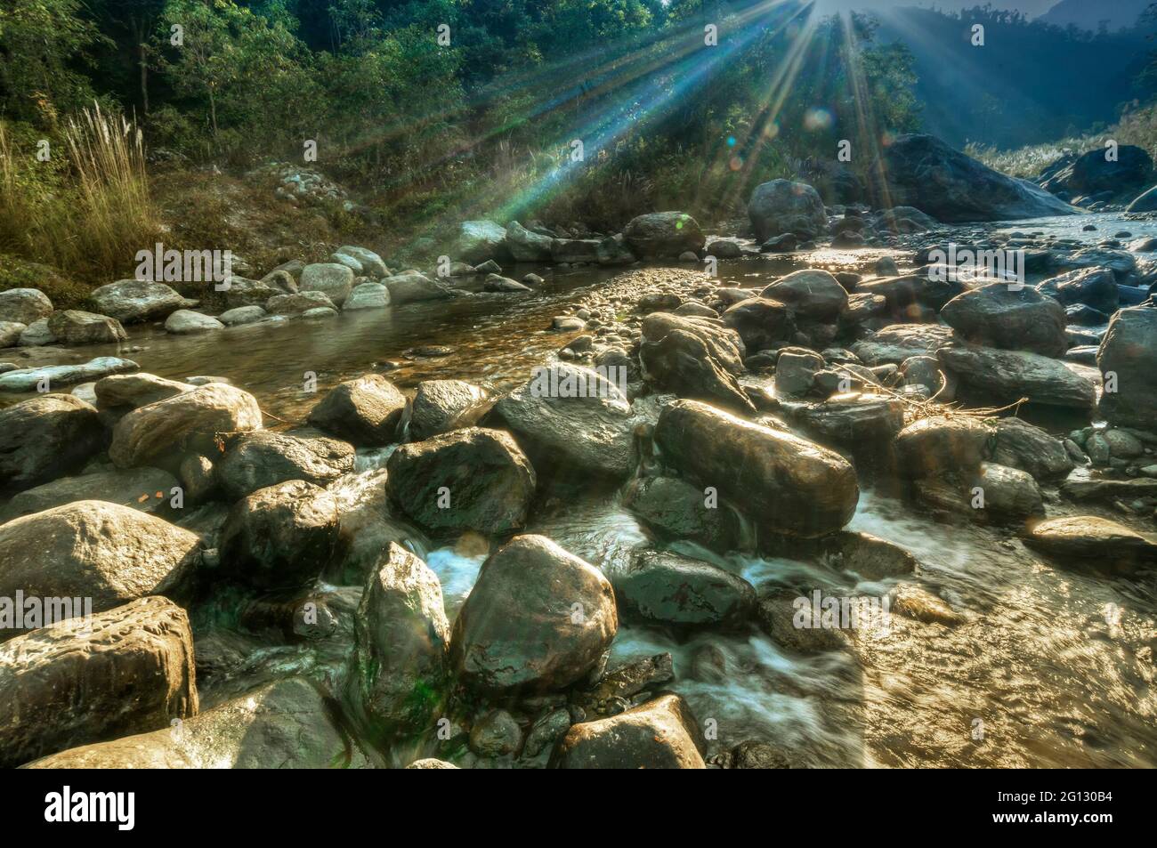 Fiume acqua che scorre attraverso le rocce all'alba, raggi di luce del sole sull'acqua, bel fiume Reshi, Sikkim, India - stock immagine dei fiumi in India Foto Stock
