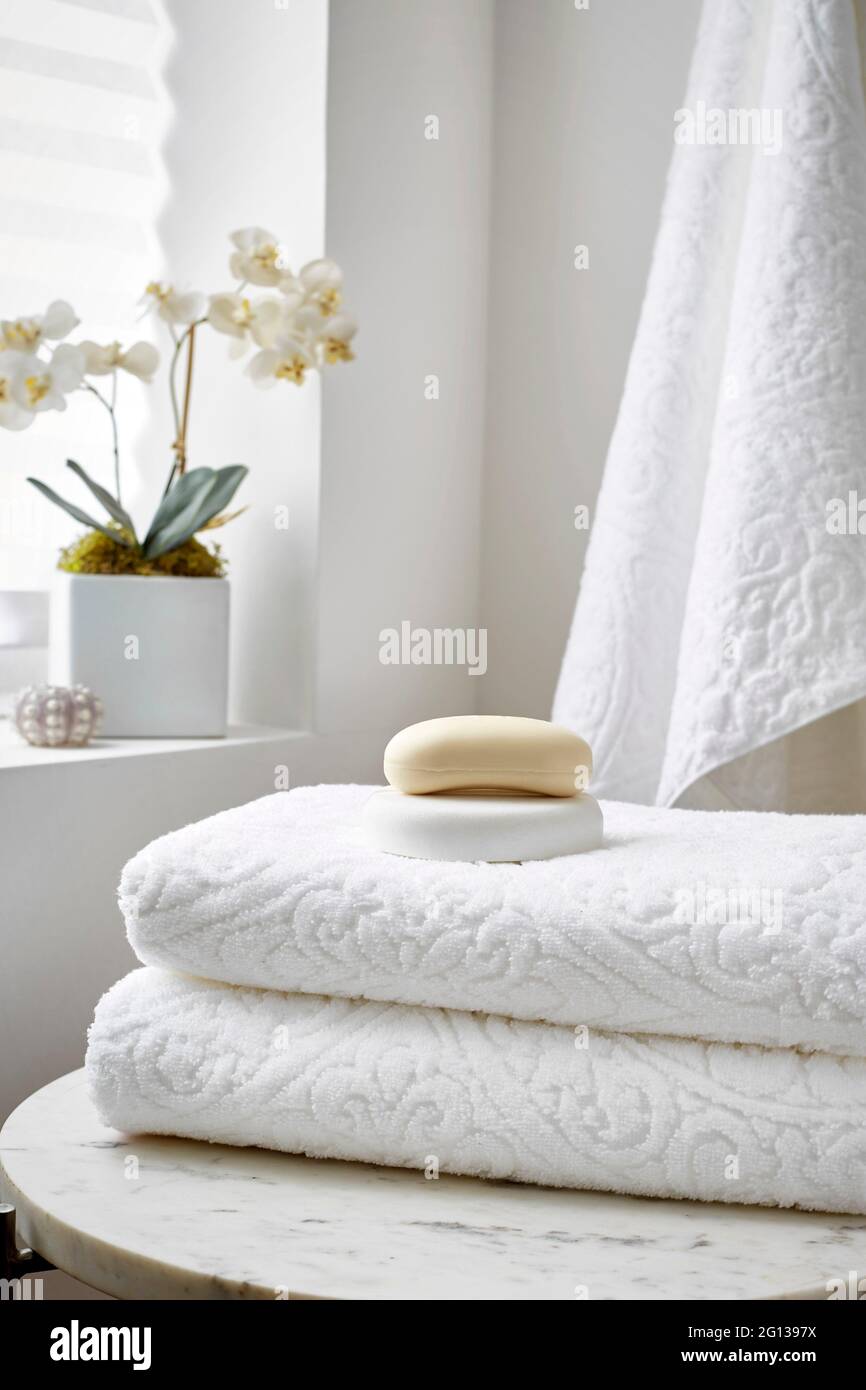 Una pila di asciugamani bianchi in un ambiente spa con sapone e una  orchidea Foto stock - Alamy
